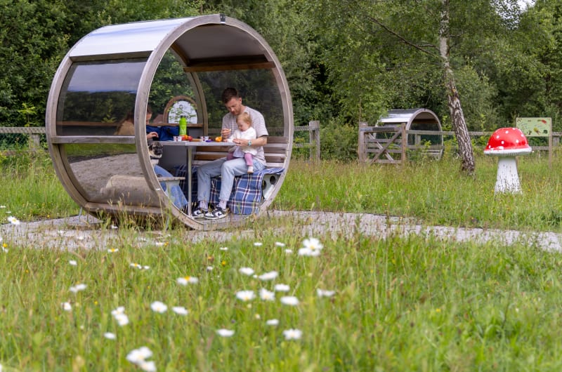 Family in outdoor cylindrical pod with giant mushroom favrcu