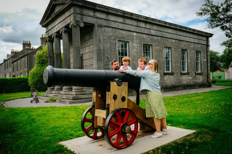 Family with historic cannon outside stone building axwbfj