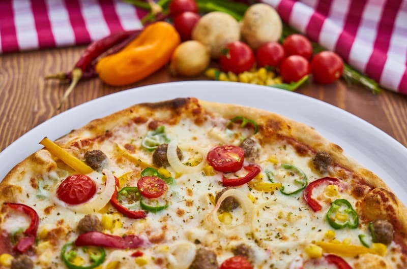 Freshly baked pizza with vegetables on wooden table uiy2wd