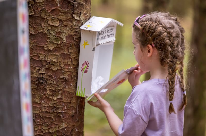 Girl Looking Inside A Wooden Fairy Letter Box drb93f