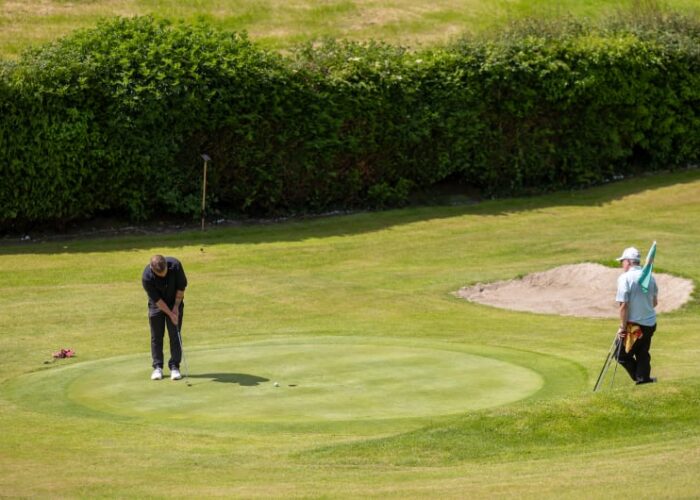 Golfer Putting On Green Near Sand Bunker b3ak00