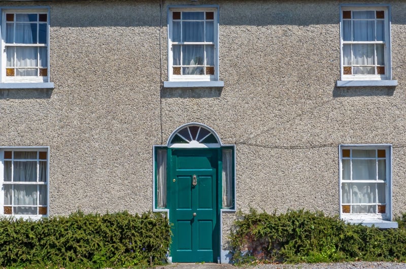 Green Door And Sash Windows On Textured Facade jfszgo