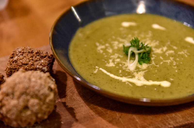 Green Soup Garnished With Herbs And Bread Rolls