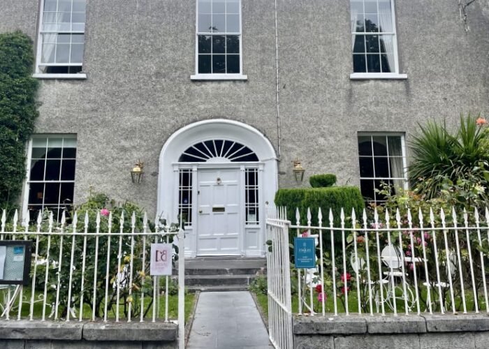 Grey building with white door and picket fence nczngd