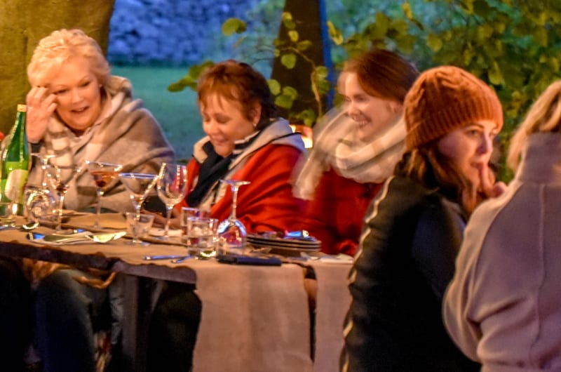 Group Dining Outdoors Under Trees With String Lights
