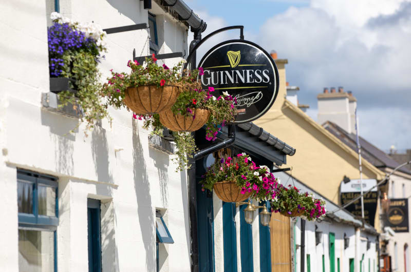 Guinness Sign And Hanging Flowers On White Building ebhyxz