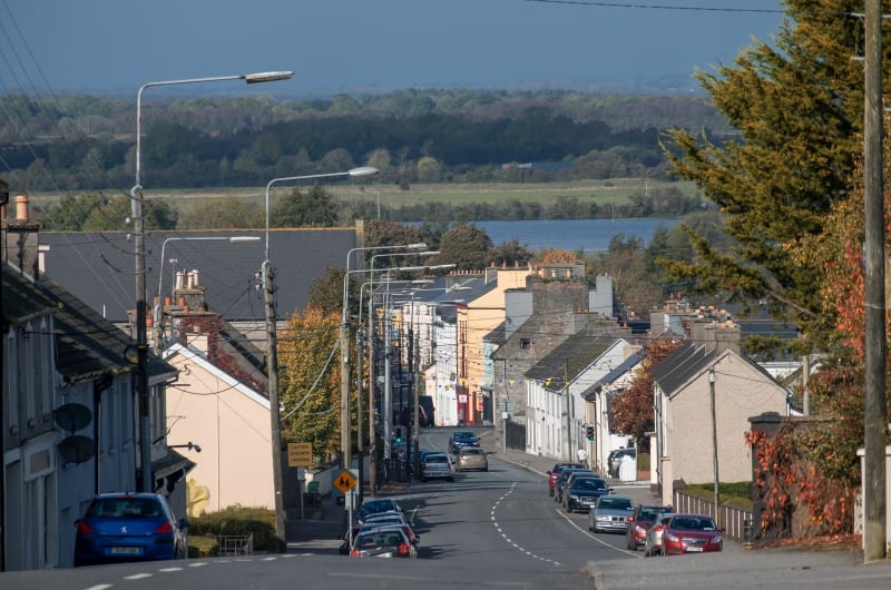 Hilly Irish Street Overlooking Lake With Cars j2mhc4