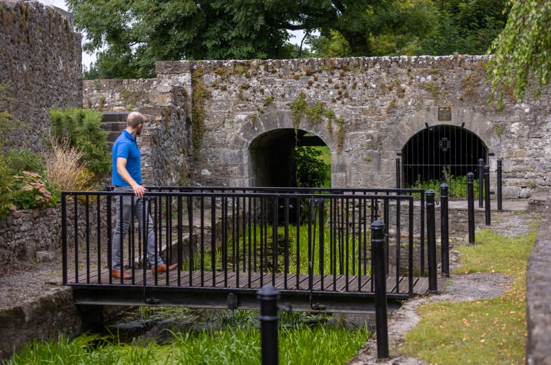 Man Standing On Bridge Near Historical Stone Ruins wu8n6r