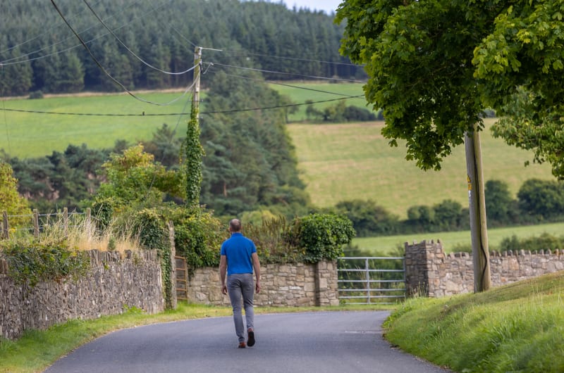 Man Walking Away On Rural Countryside Road uj2d2u