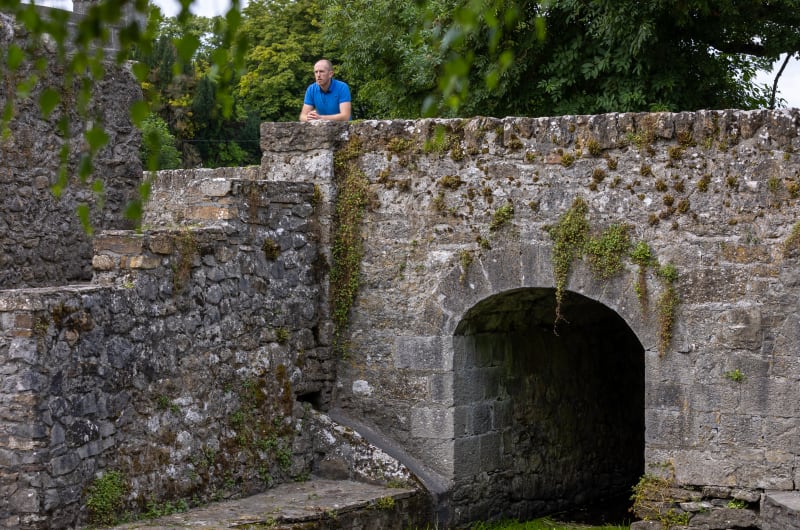 Man in blue shirt on stone bridge arch ropi9s