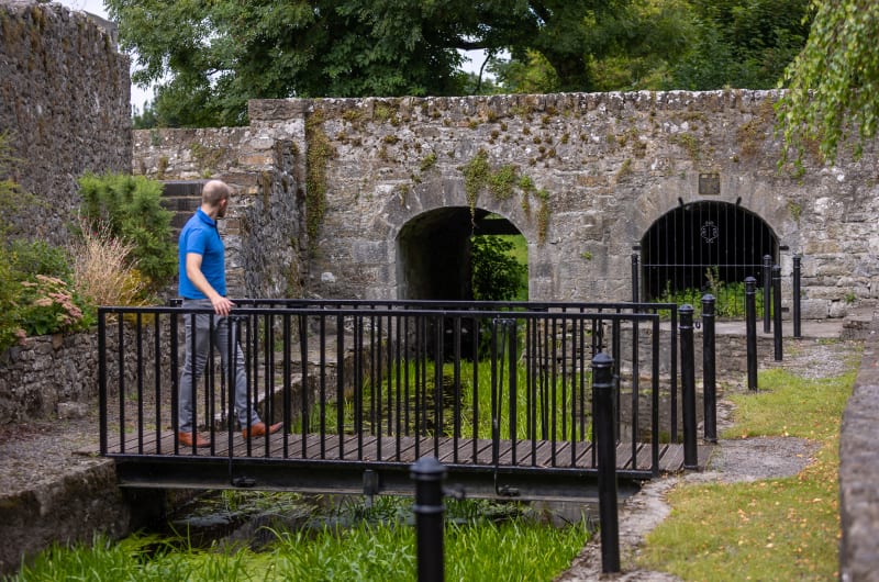 Man standing on footbridge near stone ruins itoxtn