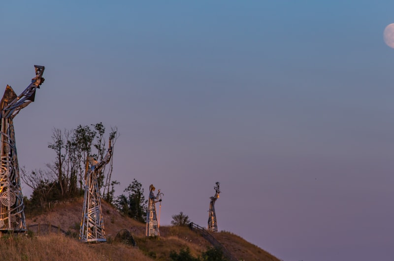 Metal sculptures on hillside under full moon l50vda