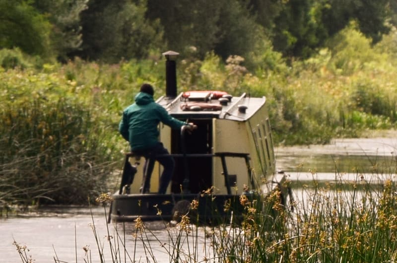 Narrowboat Navigating Canal Beside Tree Lined Towpath