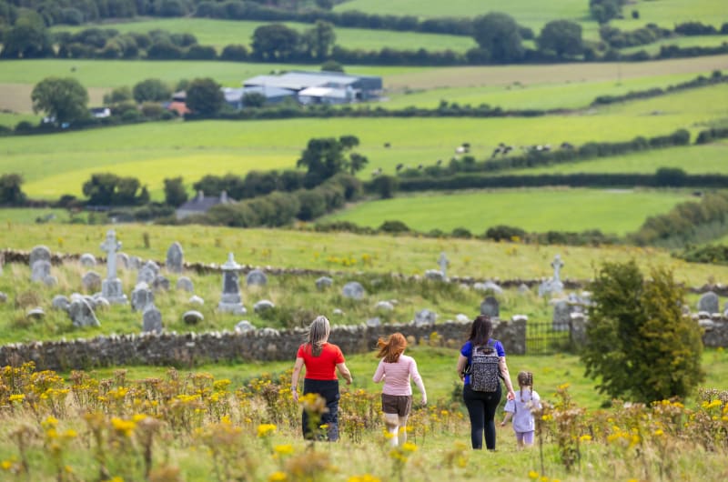 People walking towards cemetery in green countryside fsm0ha