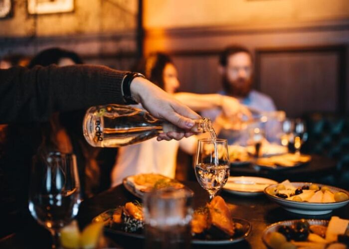 Person pouring wine into a glass during dinner evvdaq
