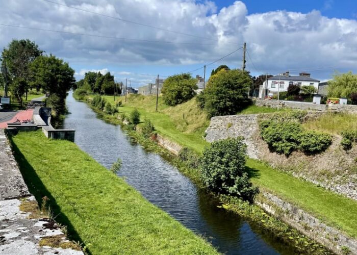 Rural Canal With Stone Walls And Grassy Banks r1gce7