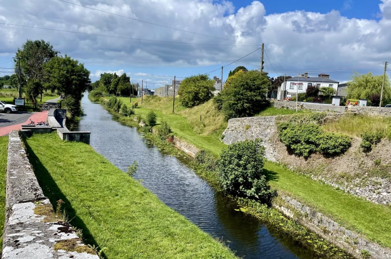 Rural Canal With Stone Walls And Grassy Banks r1gce7
