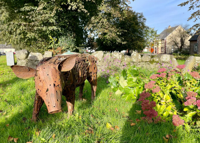 Rusty scrap metal pig sculpture standing on grass sbon3l