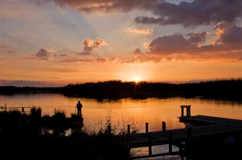 Silhouette Of Person On Lake Pier At Sunset uihdy2