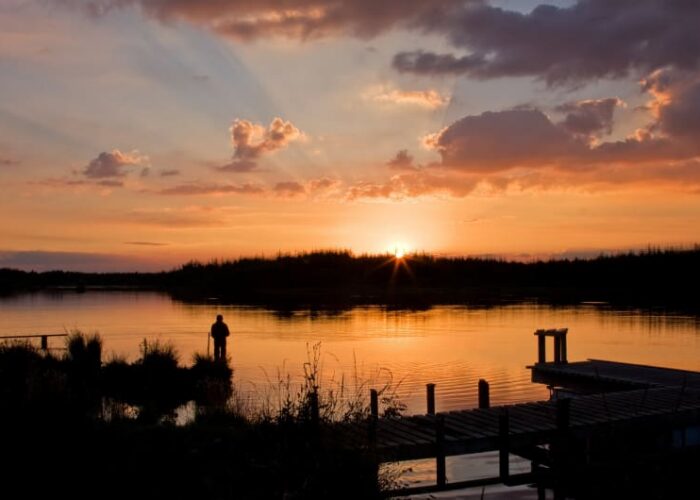 Silhouette Of Person On Lake Pier At Sunset uihdy2