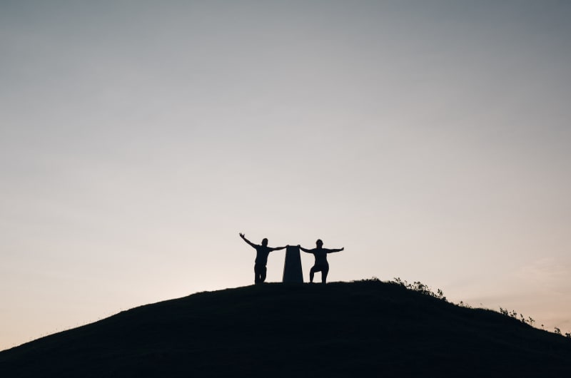 Silhouettes Of Two People At A Hill Summit s0z9yk