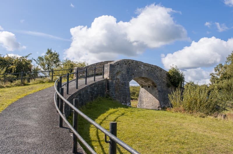 Stone Arch Bridge With Paved Path And Railing wxrjfr