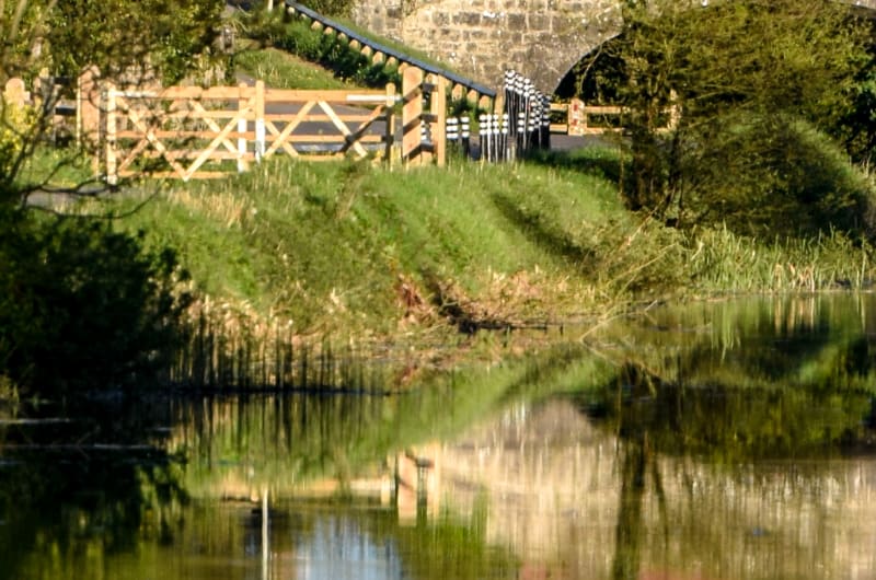 Stone Bridge Over Canal With Trees And Reflections