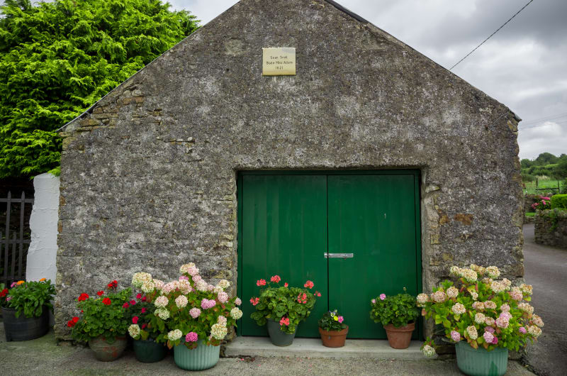 Stone Building With Green Doors And Potted Flowers mpuzhp