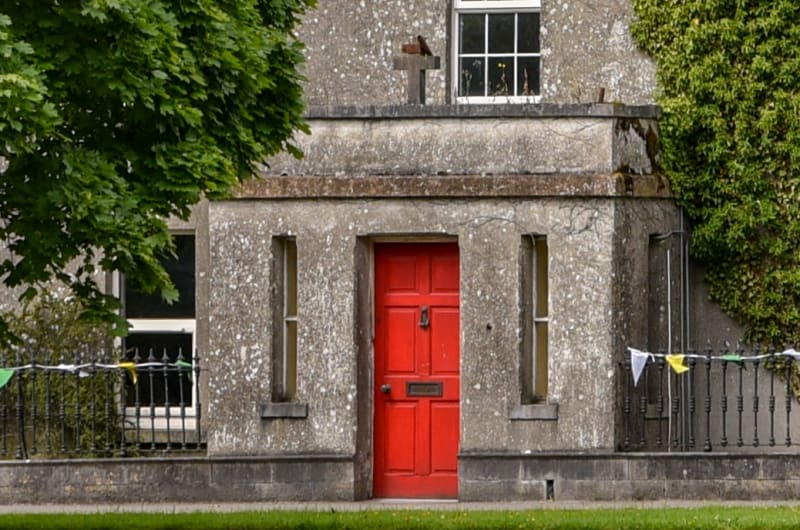 Stone Building With Red Door And Dog Statue