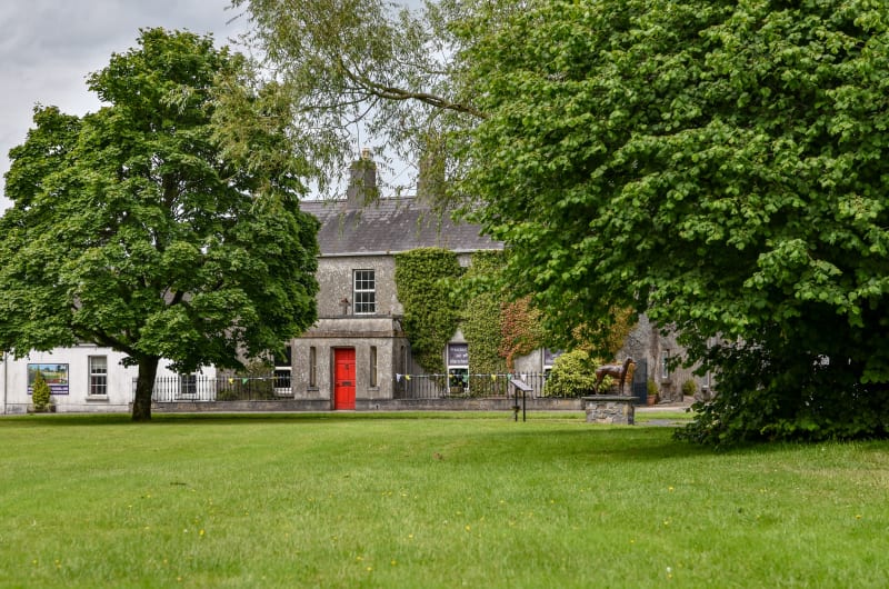 Stone Building With Red Door And Dog Statue olju8x