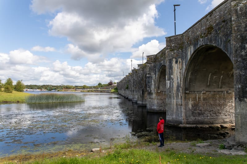 Stone arched bridge over river with onlooker fhxpzt