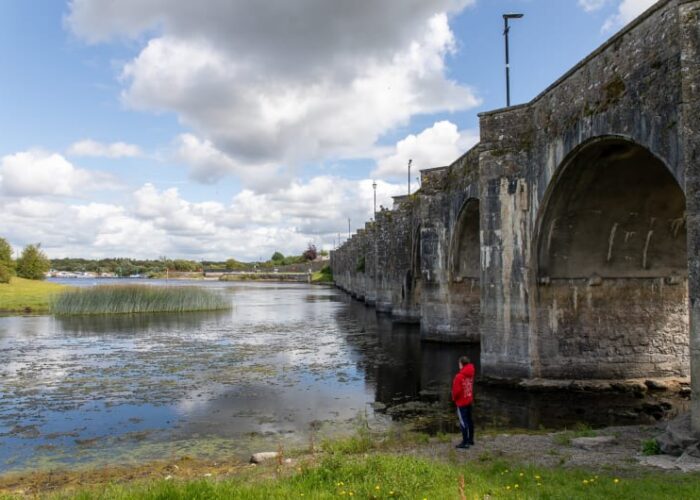 Stone arched bridge over river with onlooker fhxpzt