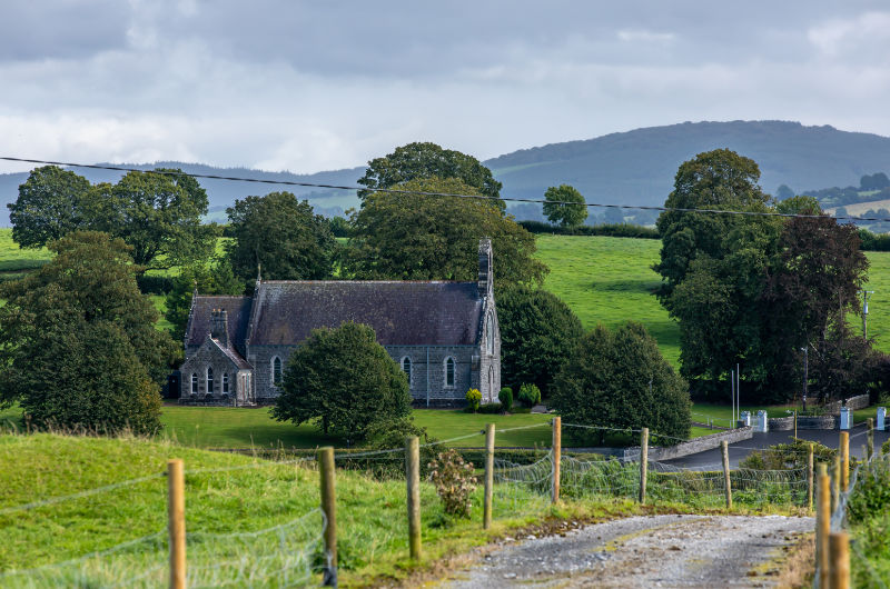 Stone church in green rural landscape with hills