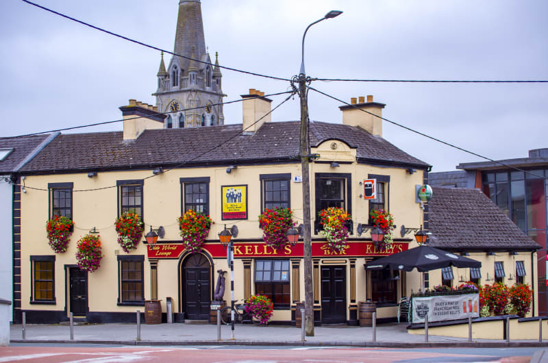Traditional yellow Irish pub Kellys Bar with flowers juskzl