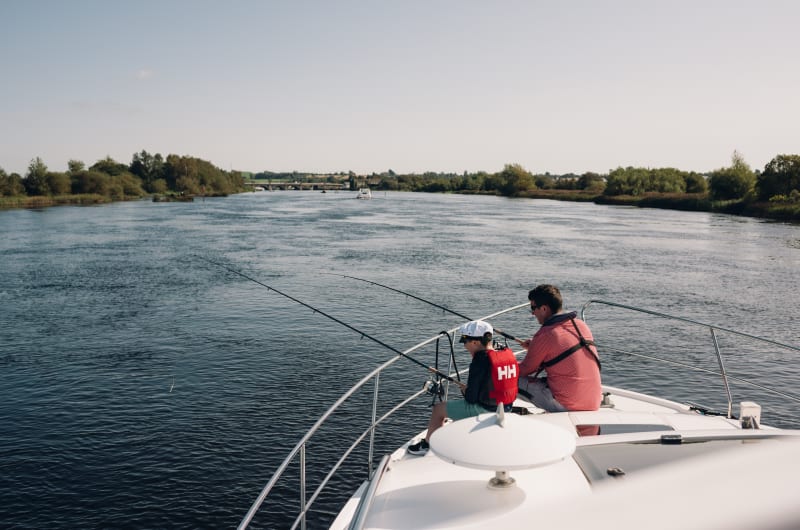 Two People Fishing From A Boat On River