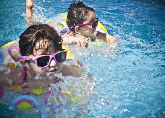 Two girls wearing sunglasses splashing in swimming pool ptftok