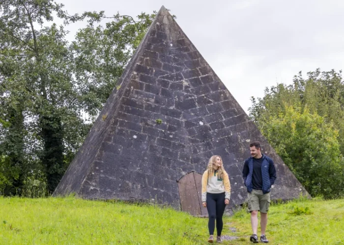 Two people walking near large stone pyramid structure lq6wmx