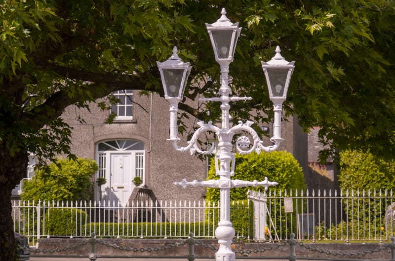 White Ornate Triple Street Light Before Stone House wt02qw