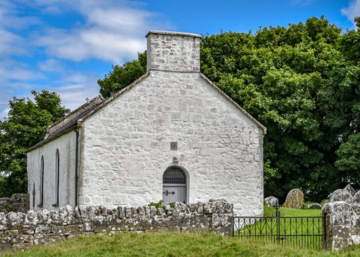 Whitewashed Stone Chapel With Graveyard And Stone Wall