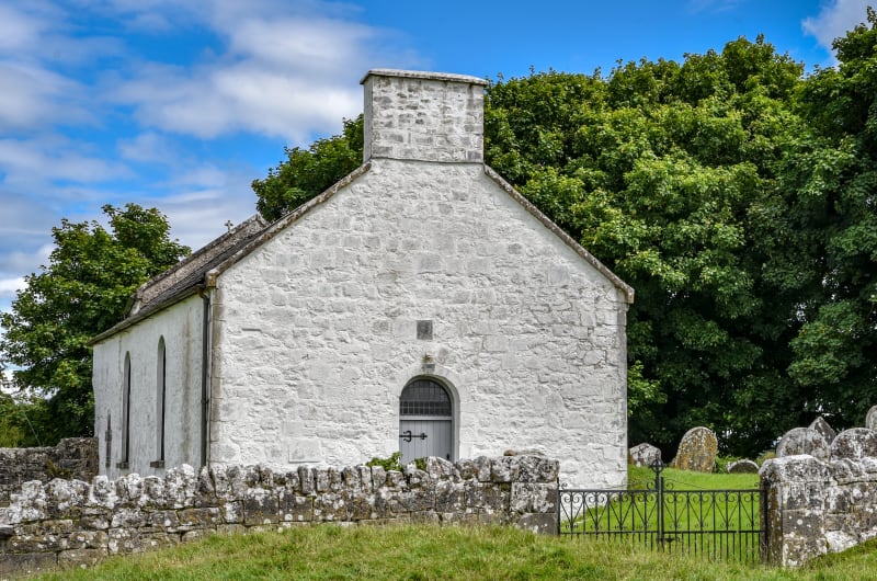 Whitewashed Stone Chapel With Graveyard And Stone Wall