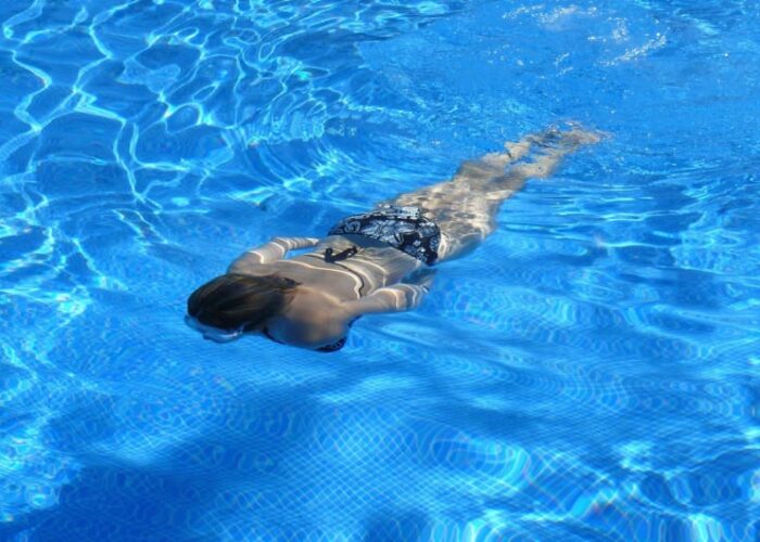 Woman Swimming Underwater In A Blue Pool may9rc