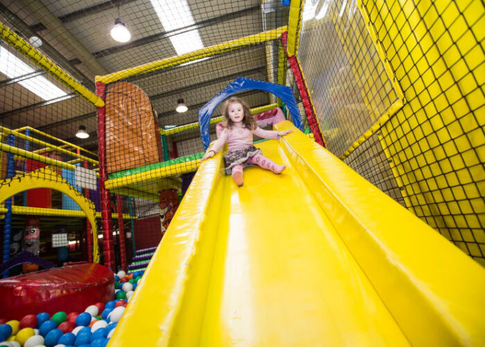Young Girl Sliding Down Yellow Slide Indoor Playground odqilj