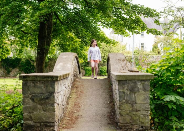 Young Girl Walking On Small Stone Bridge e8mjyh