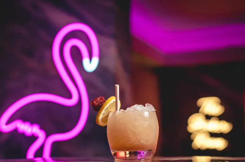 cocktail with pink flamingo neon sign in background