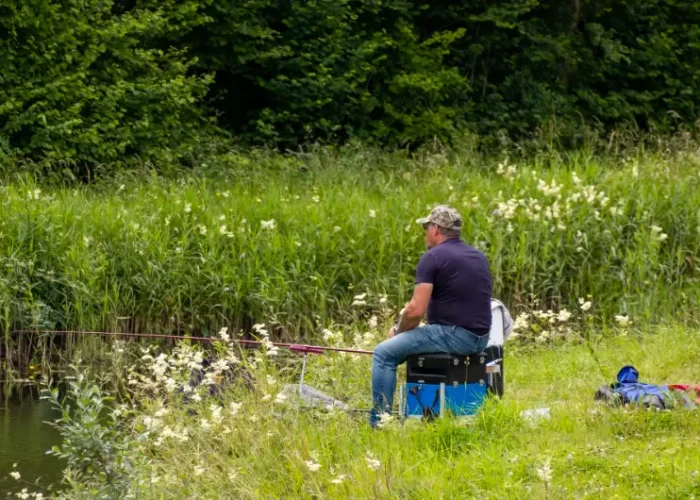 man fishing on grassy canal bank