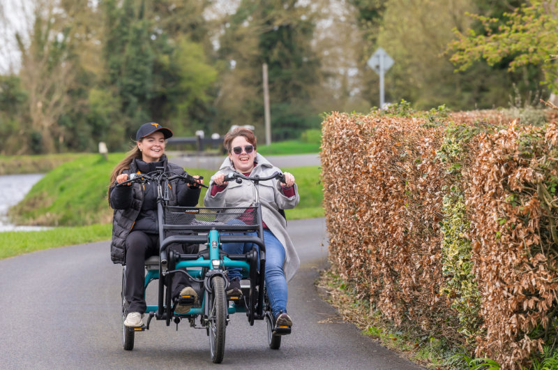 two women riding double tricycle