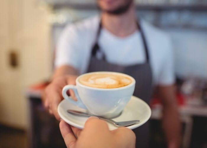 Barista Serving Cup Of Coffee To A Customer