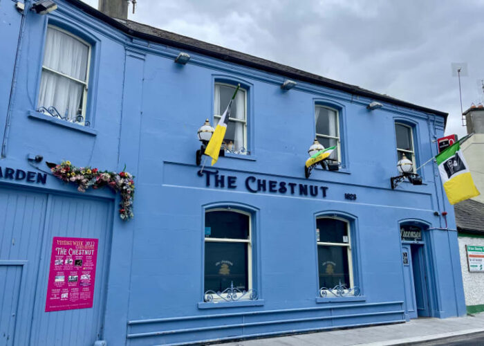 Blue exterior of The Chestnut pub with flags