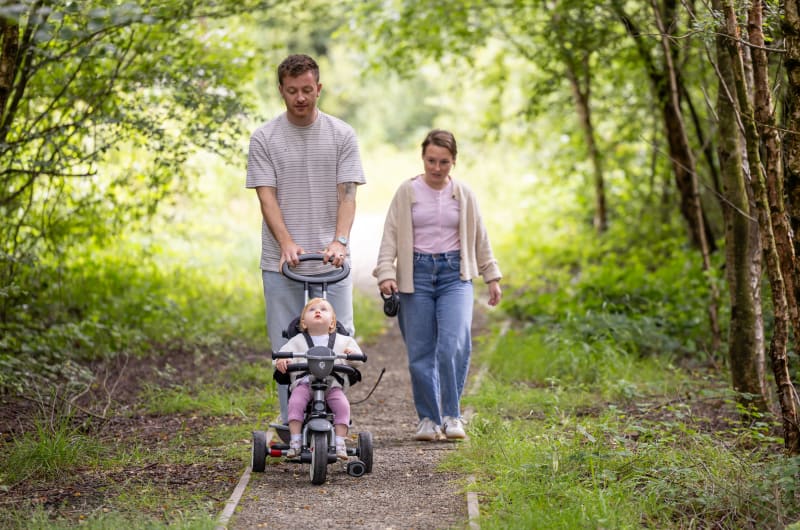 Family Walking On Forest Path With Toddler Tricycle nqspjq