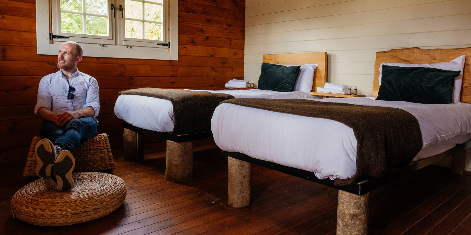 Header man sitting on basket chair in wood panel bedroom
